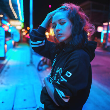 Neon close up portrait of young beautiful woman wear hoodie. night city street shot